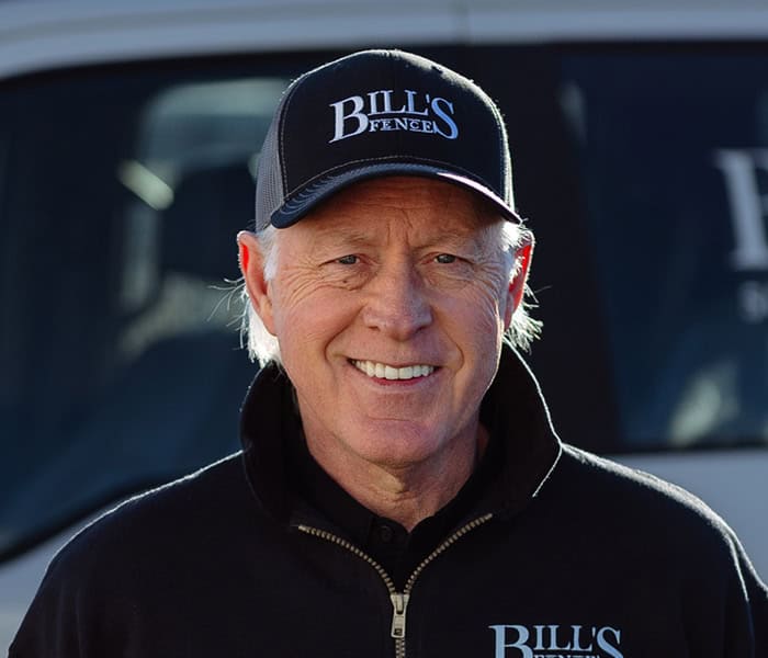 Lance Pabst wearing a Bills Fence cap and zip-up jacket smiles outdoors, standing in front of a vehicle with the Bills Fence logo visible in the background.