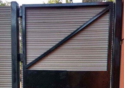 A metal gate with a diagonal support bar is installed, but the bar prevents the gate from opening because it hits the adjacent frame. The gate appears nonfunctional due to the design flaw.