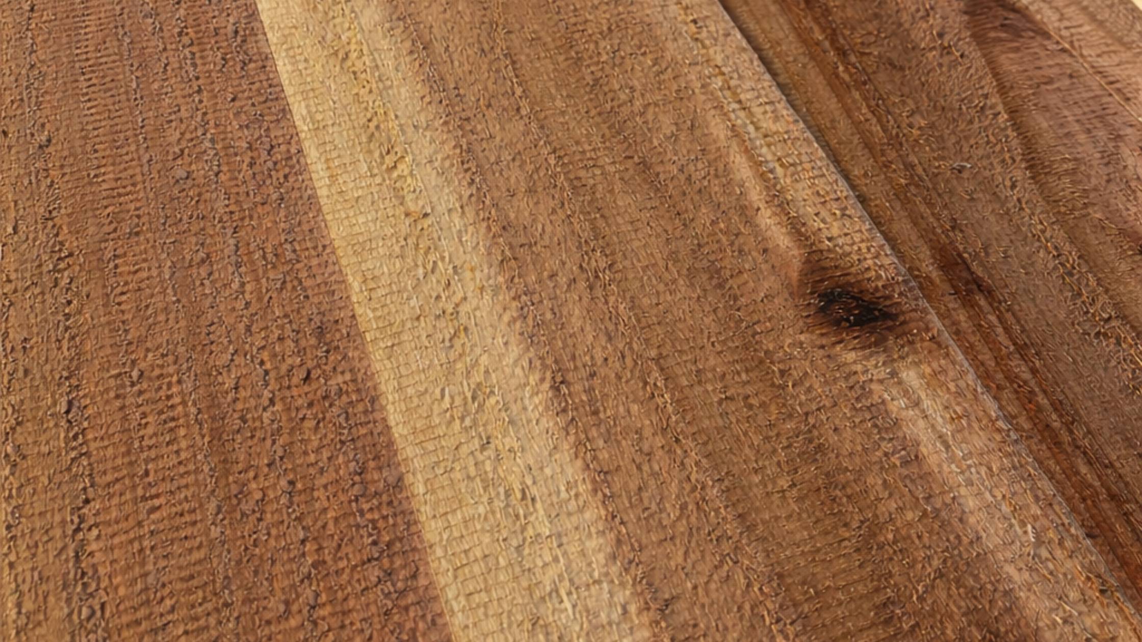Close-up of a textured wooden surface with visible grain patterns, rough saw marks, and a natural knot, showcasing a mix of light and dark brown tones.